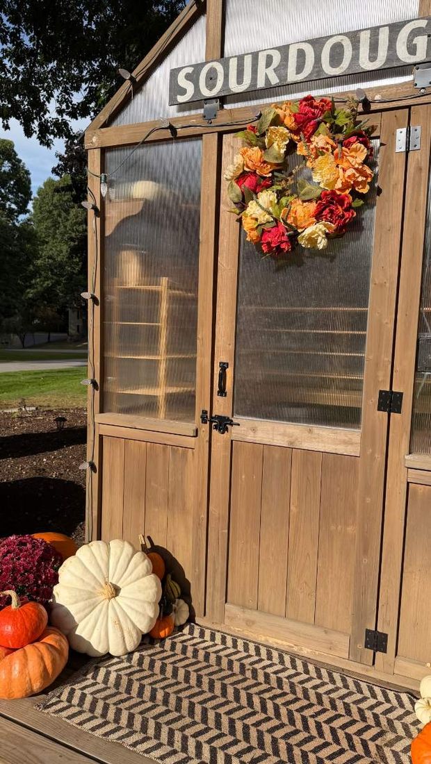 The shed with a fall wreath and pumpkins