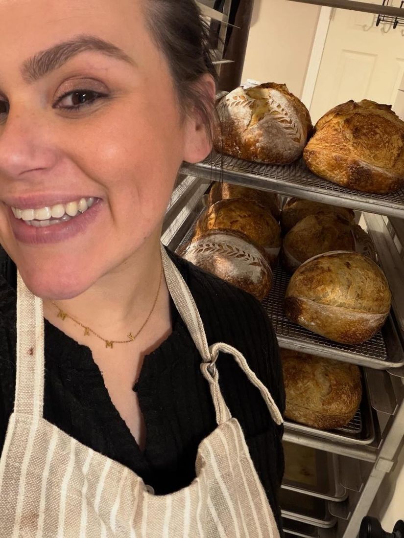 Tory smiling beside racks of fresh loaves
